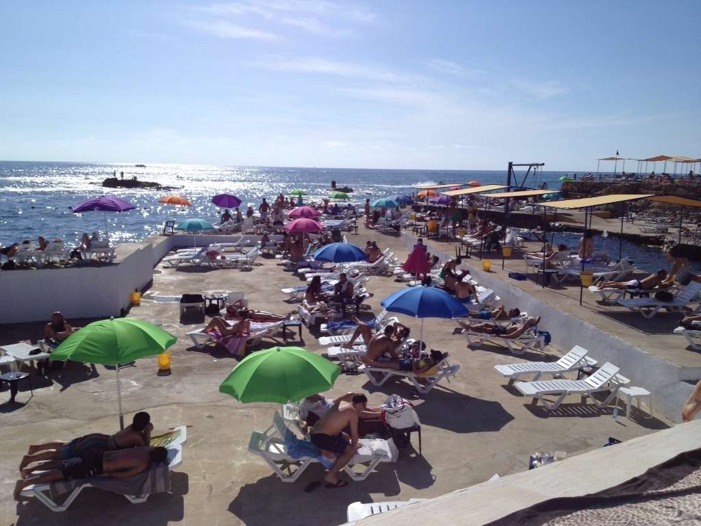 Swimmers on the rocky coast and decks at Sporting Club Beach