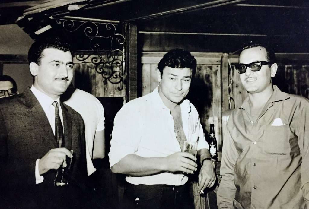 Three men with drinks at the Sporting Club Beach bar — an archive photograph