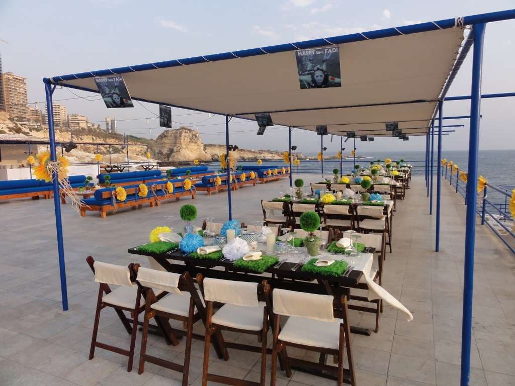 A private celebration set up on the terrace at Sporting Club Beach, tables under the canopy by the sea