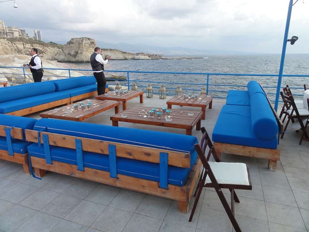 The event terrace at Sporting Club Beach set with daybeds and lantern tables by the sea