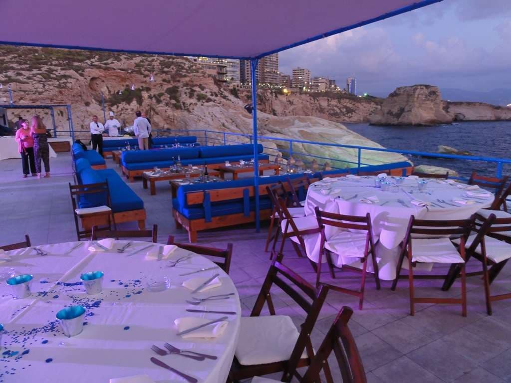 A banquet set up on the terrace at Sporting Club Beach at dusk, the Pigeon Rocks beyond