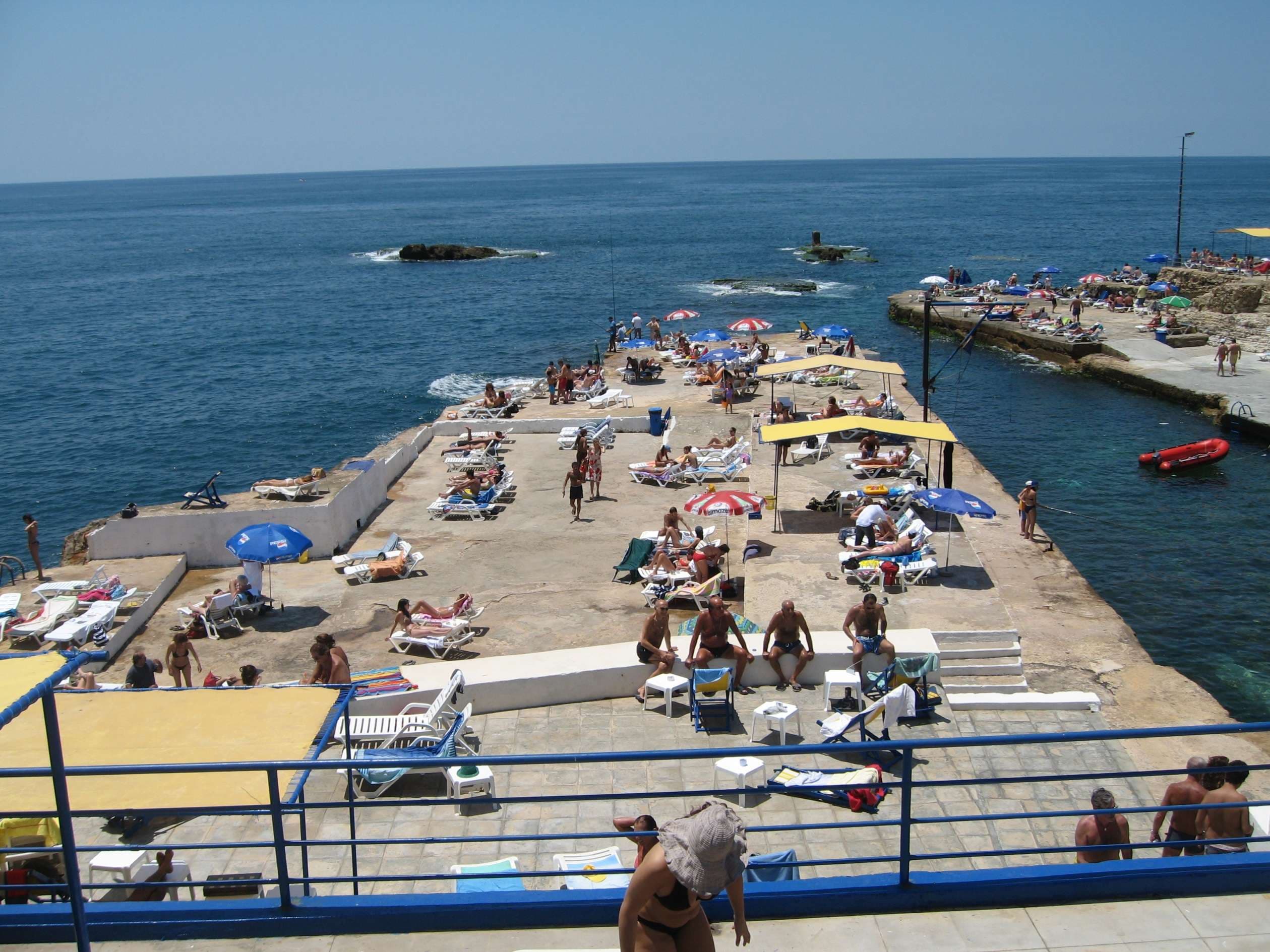 Sunbathers on the concrete bathing piers reaching into the open sea at Sporting Club Beach, Ras Beirut