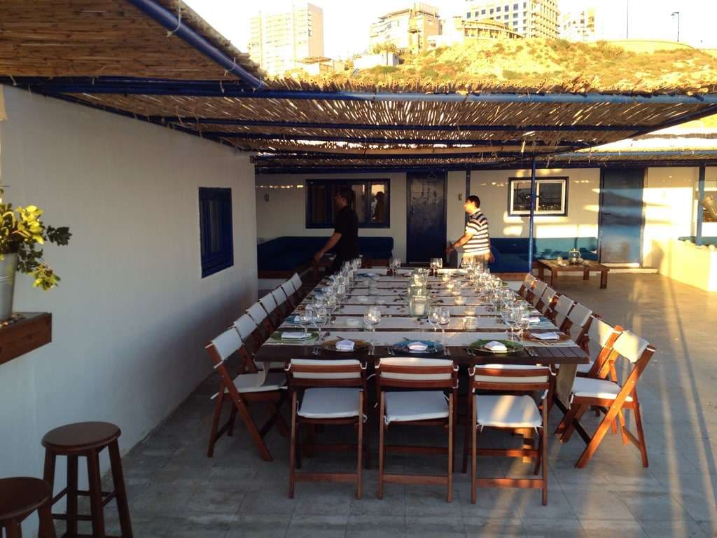 A long table set for a meal under a reed canopy on the terrace at Sporting Club Beach, Ras Beirut