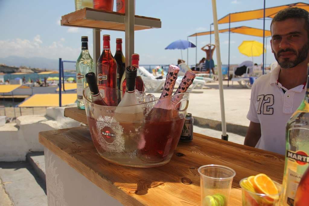 A seaside drinks bar set with bottles and fresh fruit at Sporting Club Beach