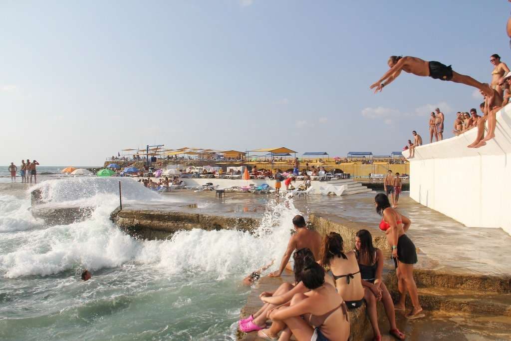 A swimmer leaping into the Mediterranean off the rocks at Sporting Club Beach
