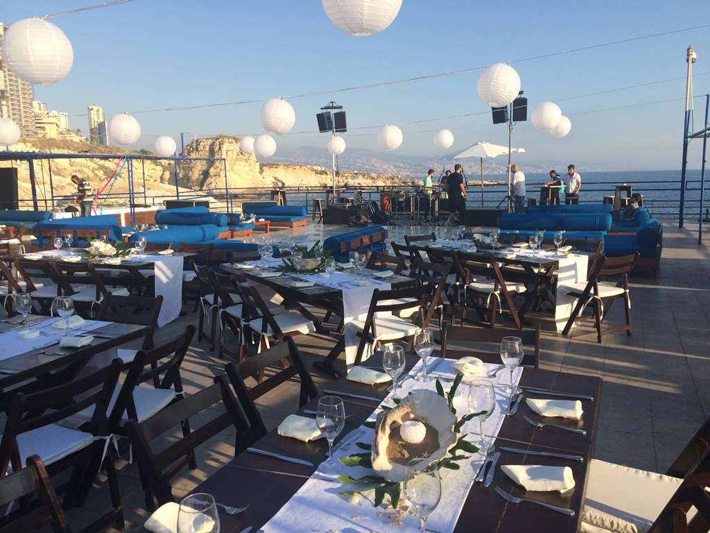 A wedding dinner set on the seafront terrace under paper lanterns at Sporting Club Beach