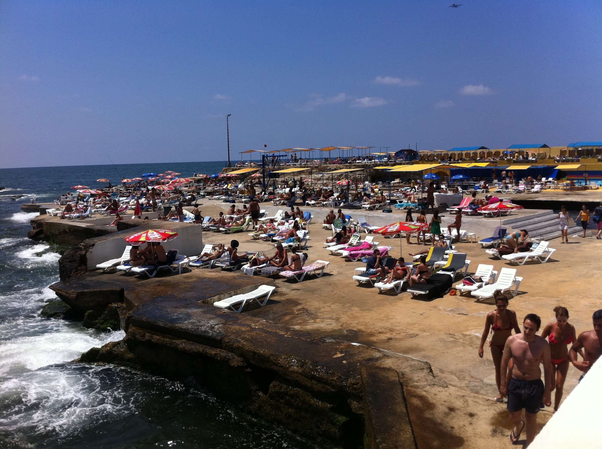 A crowded summer day across the pool decks and bathing terraces at Sporting Club Beach, Ras Beirut