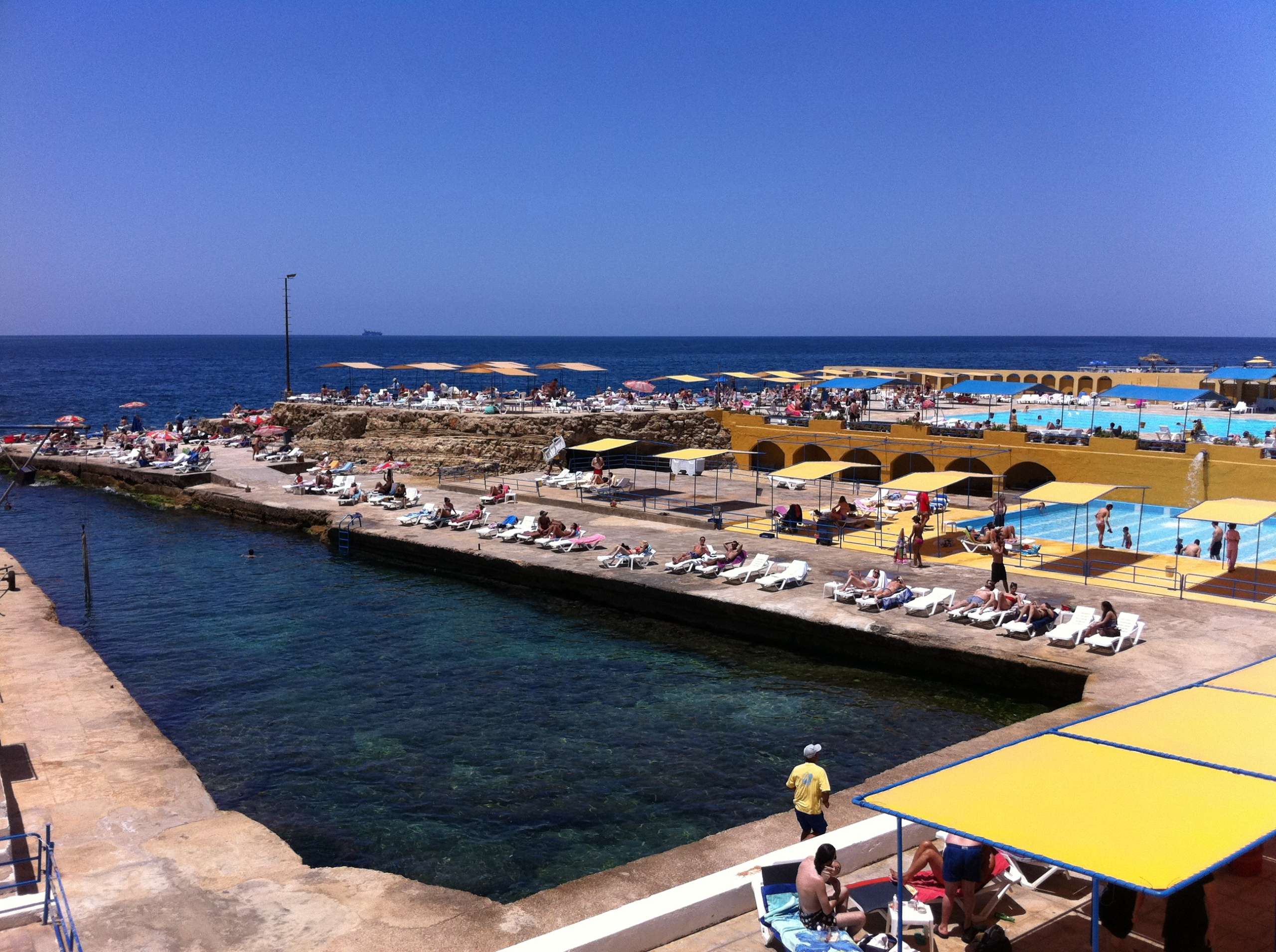 The saltwater pools and decks stretching along the rocky shoreline at Sporting Club Beach