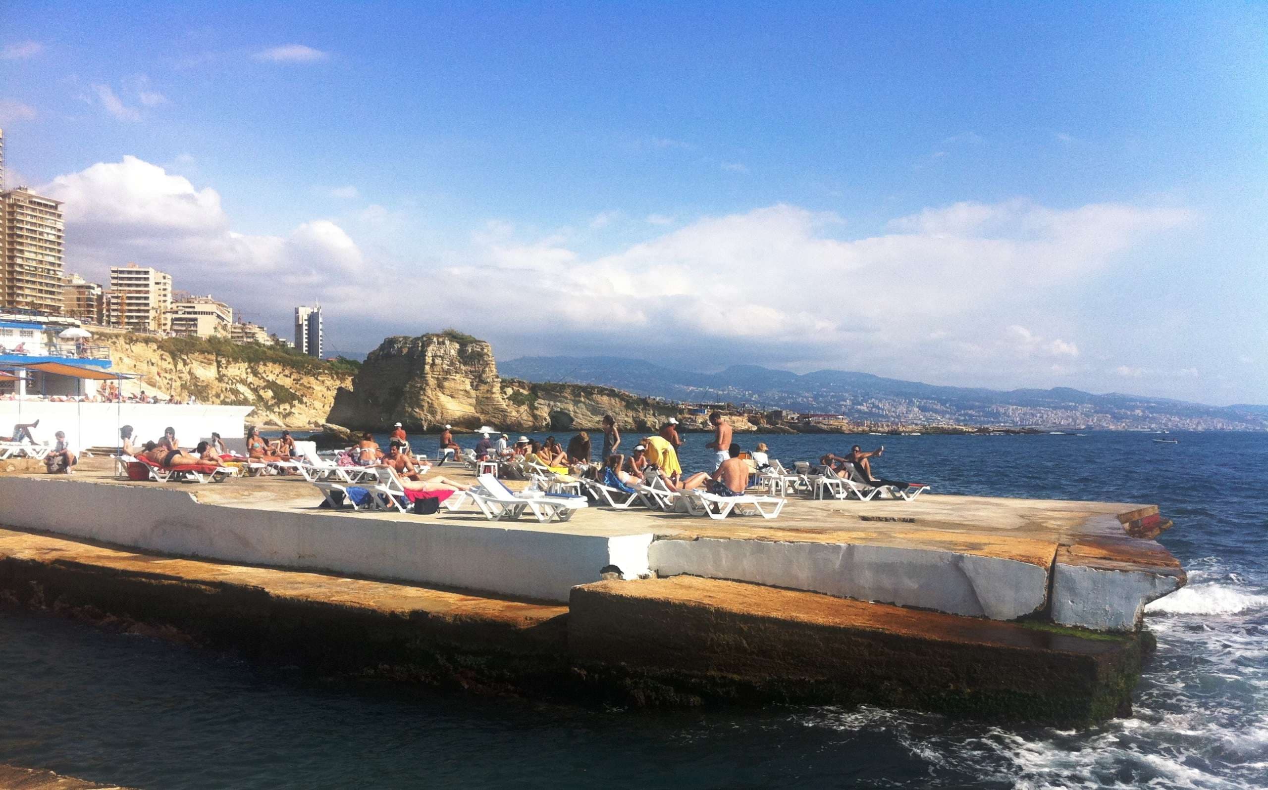 Bathers on the seafront deck with the Beirut coastline behind at Sporting Club Beach, Ras Beirut