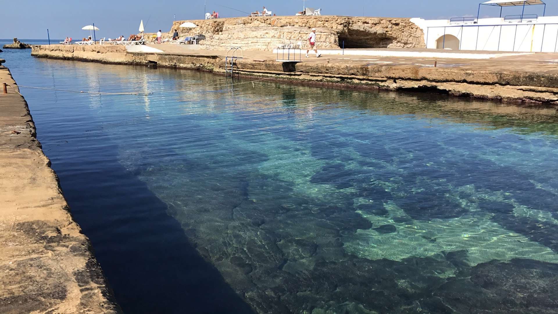 Shallow, clear water among the rocks on the natural shoreline at Sporting Club Beach