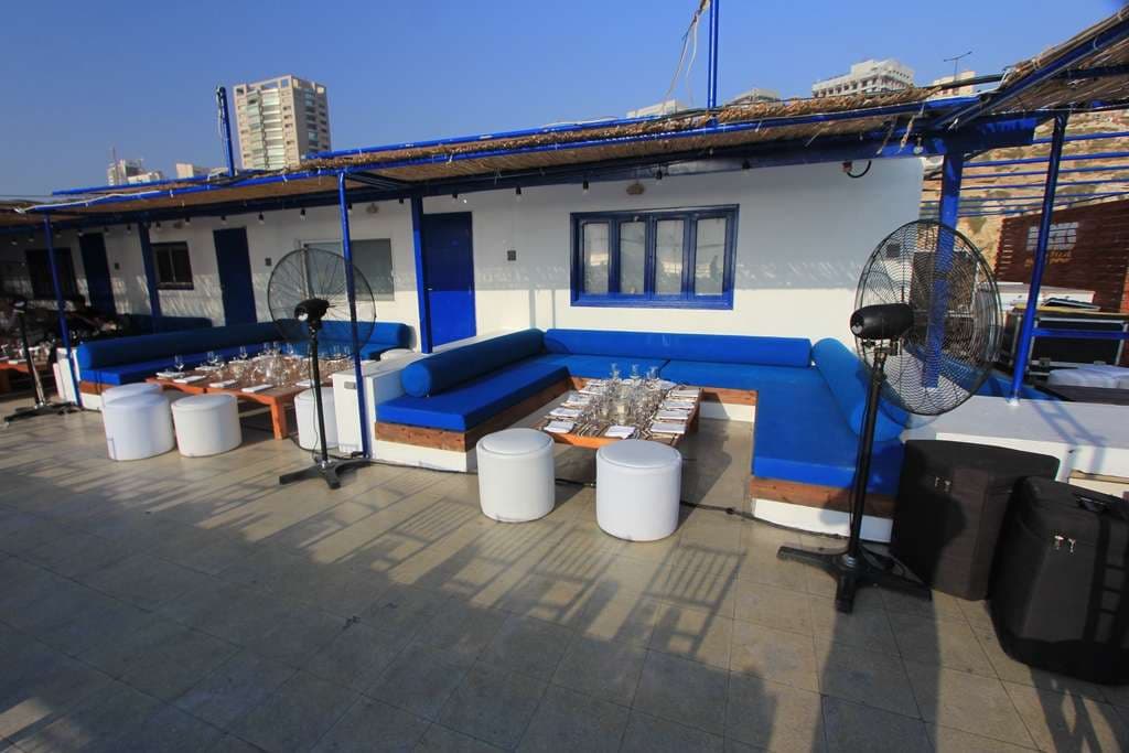 A blue-and-white seaside lounge set with cushioned banquettes at Sporting Club Beach