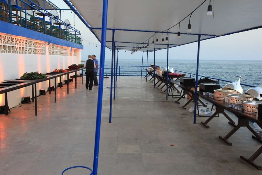 A seafront buffet being prepared at dusk along the terrace at Sporting Club Beach