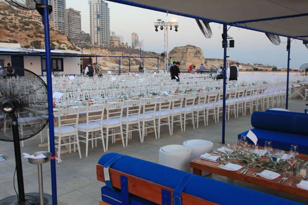 Long banquet tables and lounge seating set on the seafront terrace at Sporting Club Beach