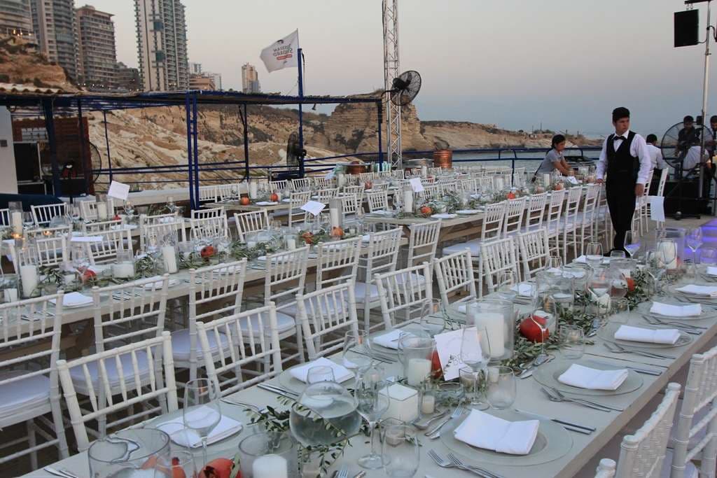A wedding banquet set with candles on the seafront terrace at dusk at Sporting Club Beach