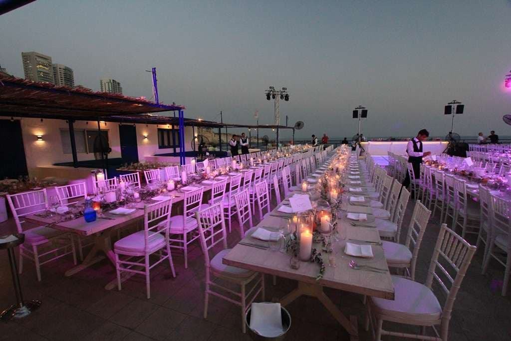 A candlelit wedding banquet set across the seafront terrace at dusk at Sporting Club Beach, Ras Beirut