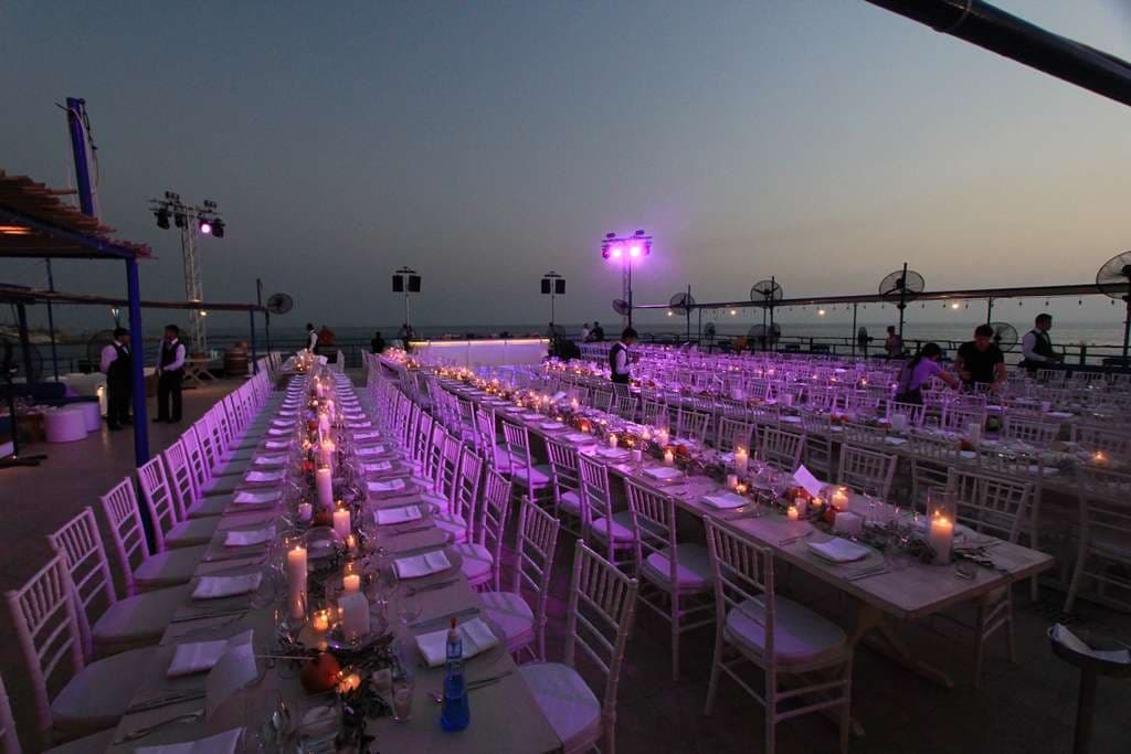 Long candlelit banquet tables set for an evening event on the seafront terrace at Sporting Club Beach, Ras Beirut