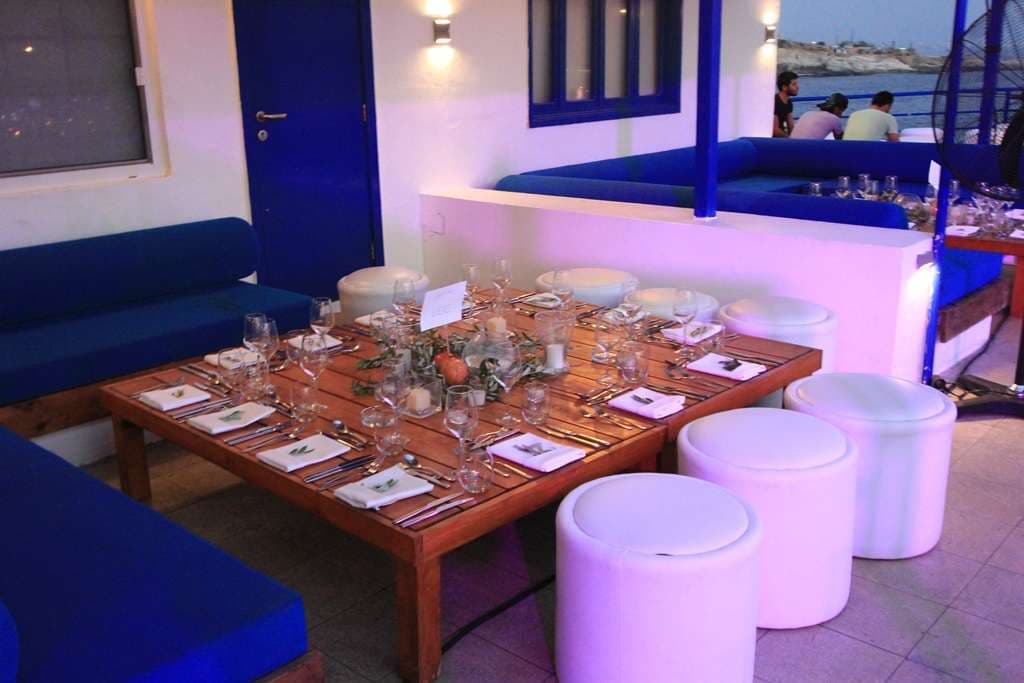 A lounge corner with blue banquettes and a set dining table at an evening event at Sporting Club Beach, Ras Beirut