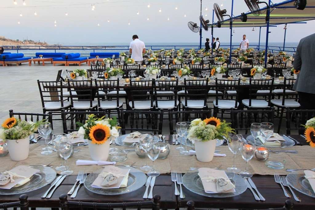 Sunflower-decorated banquet tables set on the terrace beside the sea at Sporting Club Beach, Ras Beirut