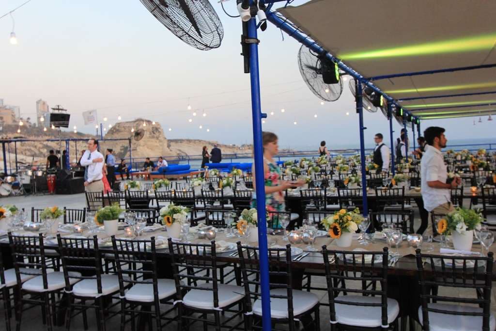Guests gathering near sunflower-set tables on the seafront event terrace at Sporting Club Beach, Ras Beirut