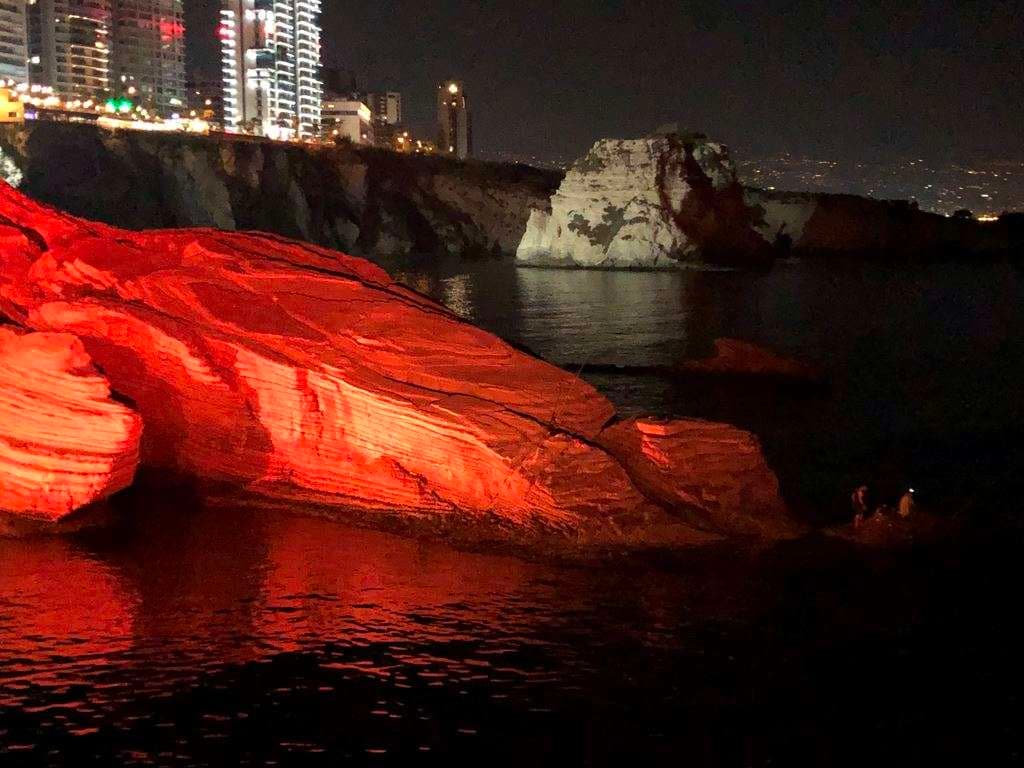 The rocky shoreline lit at night with the Pigeon Rocks and Beirut skyline beyond at Sporting Club Beach, Ras Beirut