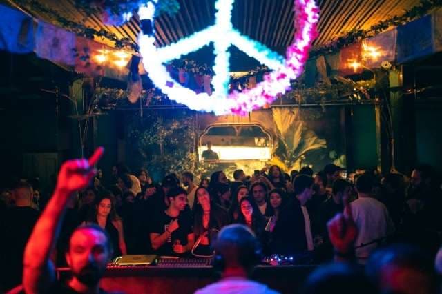 A packed dancefloor under the illuminated peace-sign at The Loft by Sporting, Sporting Club Beach