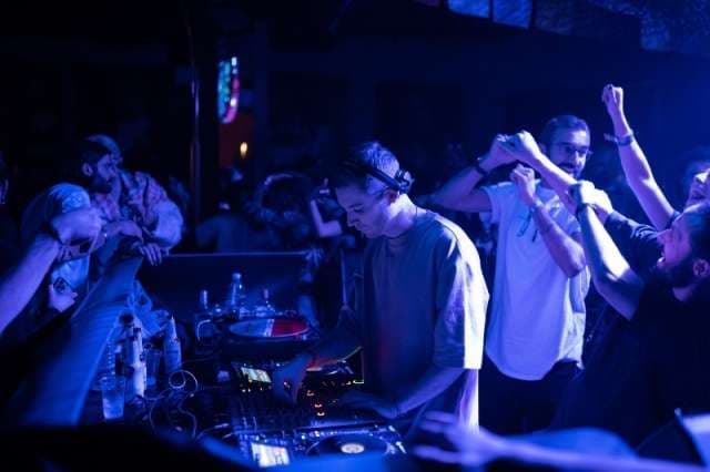 A DJ at the decks surrounded by dancers at The Loft by Sporting, Sporting Club Beach