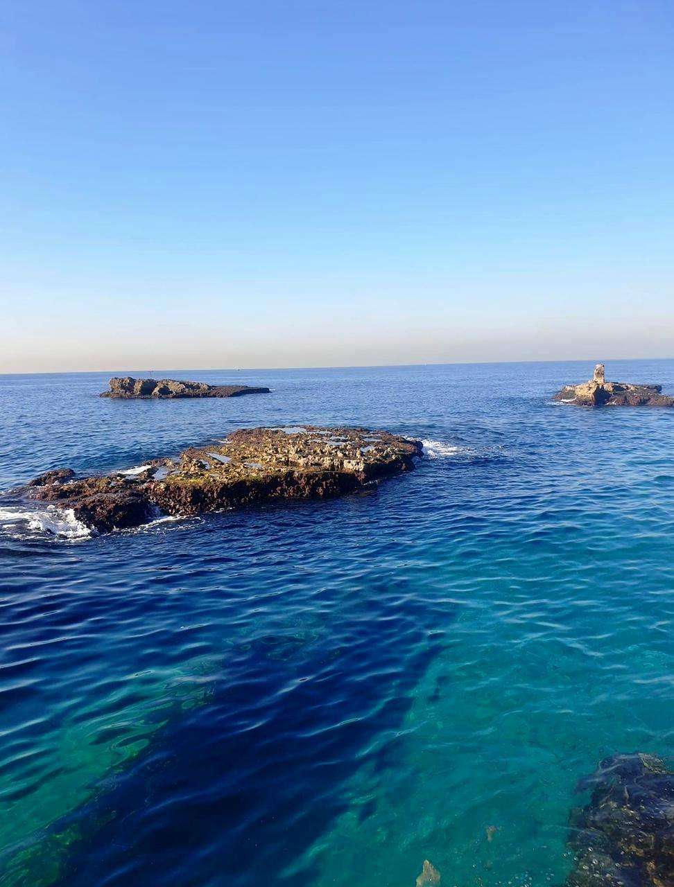 Rocky islets in clear blue water along the coastline at Sporting Club Beach, Ras Beirut