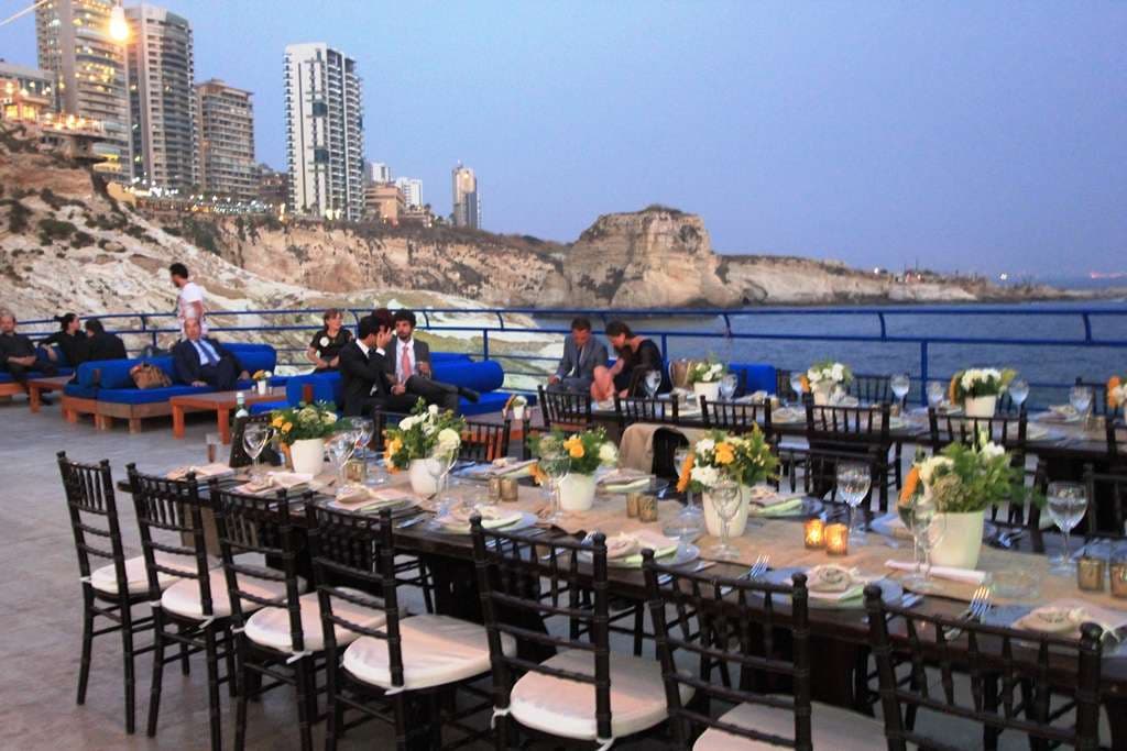 An evening event table set with flowers and candles by the sea at Sporting Club Beach, Ras Beirut