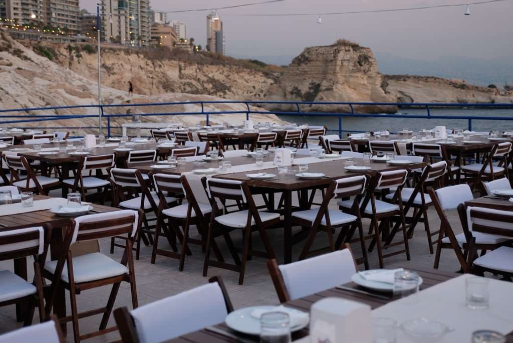 Set tables on the terrace with the rocky coast behind at Sporting Club Beach, Ras Beirut