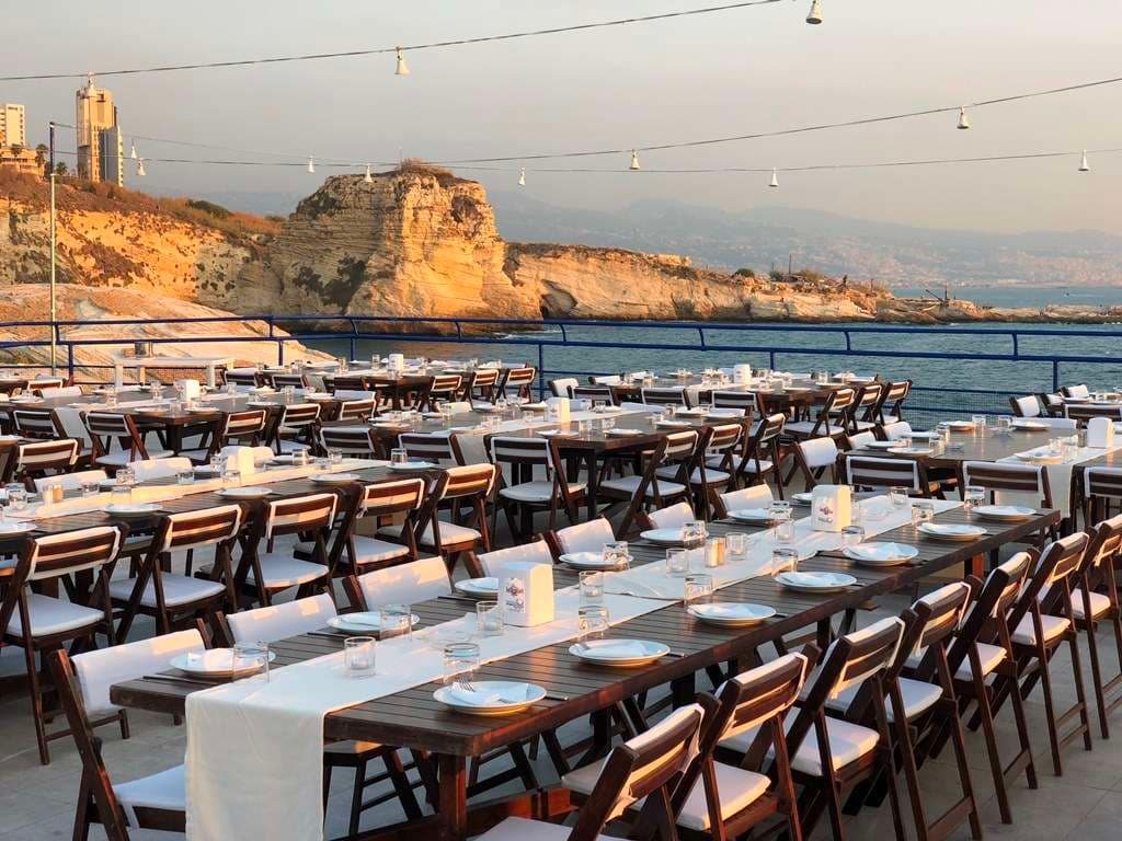 The sun setting over the sea beyond set event tables at Sporting Club Beach, Ras Beirut