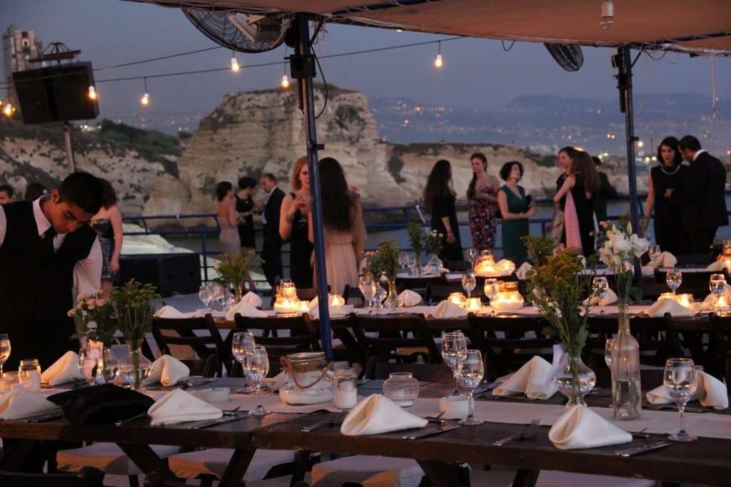 Set tables strung with lights at sunset with Beirut behind at Sporting Club Beach, Ras Beirut