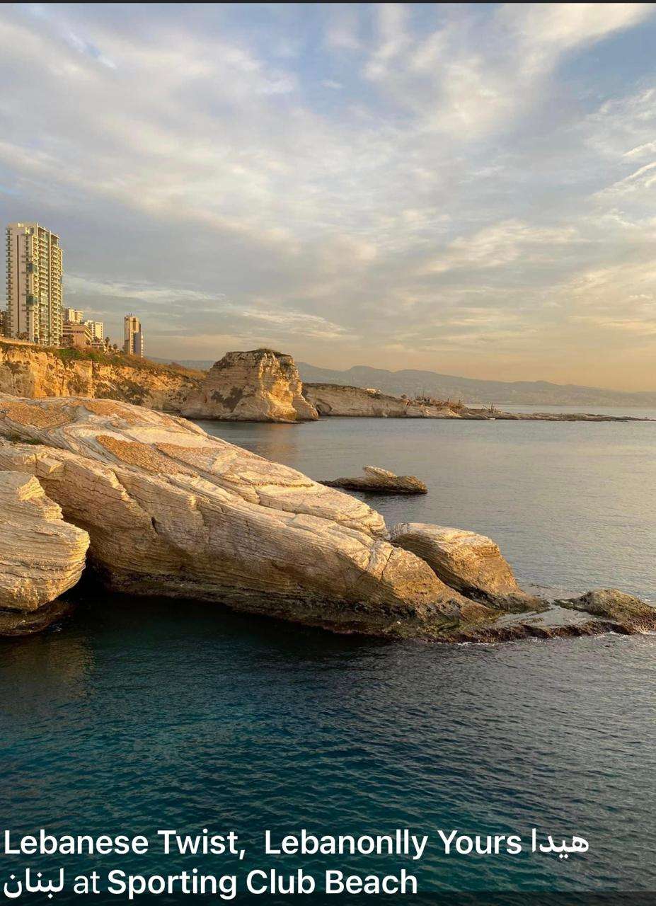 The rocky coastline at sunset with the Pigeon Rocks and Beirut behind at Sporting Club Beach, Ras Beirut
