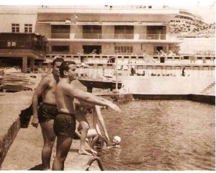 Young men by the pool with the club building behind at Sporting Club Beach — an archive photograph