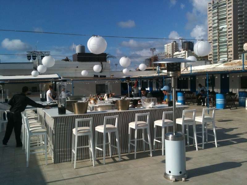 An open-air bar with white stools and paper lanterns set up on the terrace at Sporting Club Beach, Ras Beirut