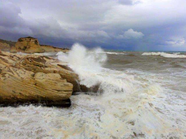 Waves breaking against the layered rock formations of the Ras Beirut coastline at Sporting Club Beach