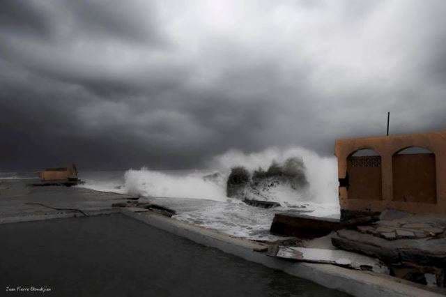 A storm wave breaking beside an empty pool under a heavy sky at Sporting Club Beach, Ras Beirut
