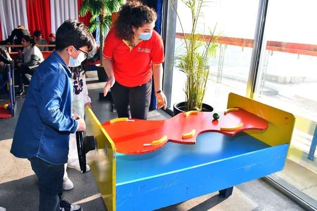A staff member helping a child at a game table during a party inside The Loft at Sporting Club Beach