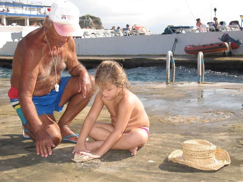 A man and a child examining shells on the rocky shoreline at Sporting Club Beach, Ras Beirut
