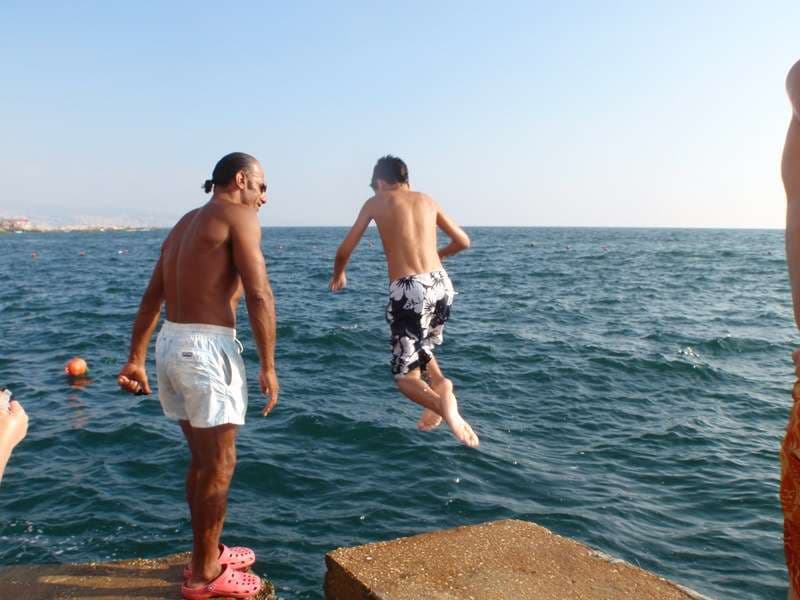 Swimmers jumping into the sea from a rocky ledge at Sporting Club Beach, Ras Beirut
