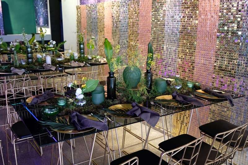 A set dining table with gold plates and greenery in The Loft at Sporting Club Beach
