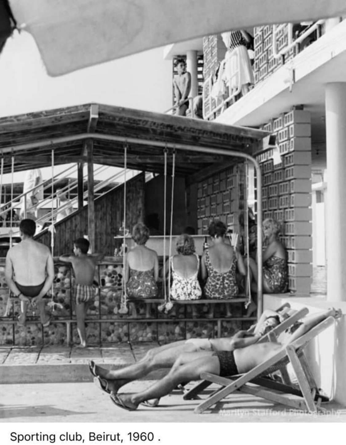 Members on a poolside swing and sun loungers at Sporting Club Beach in 1960 — an archive photograph