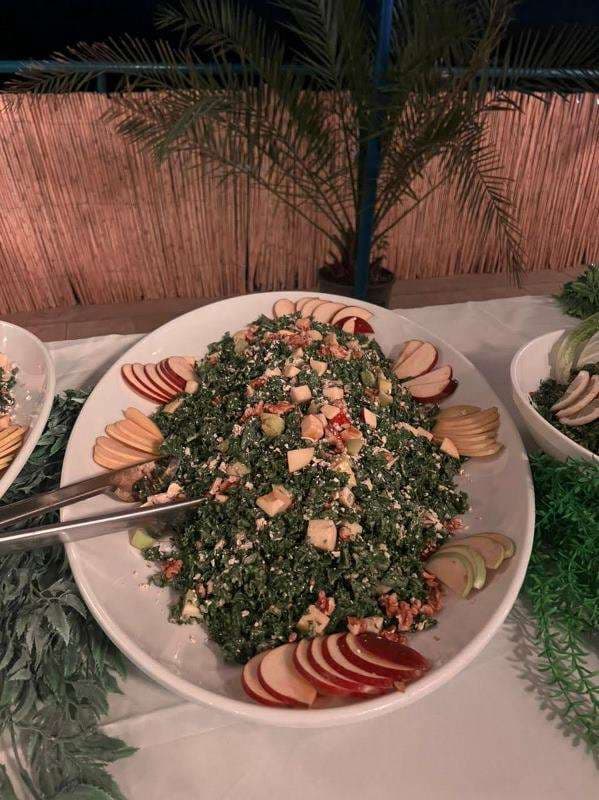 A composed tabbouleh salad with apple slices on a serving platter at Sporting Club Beach