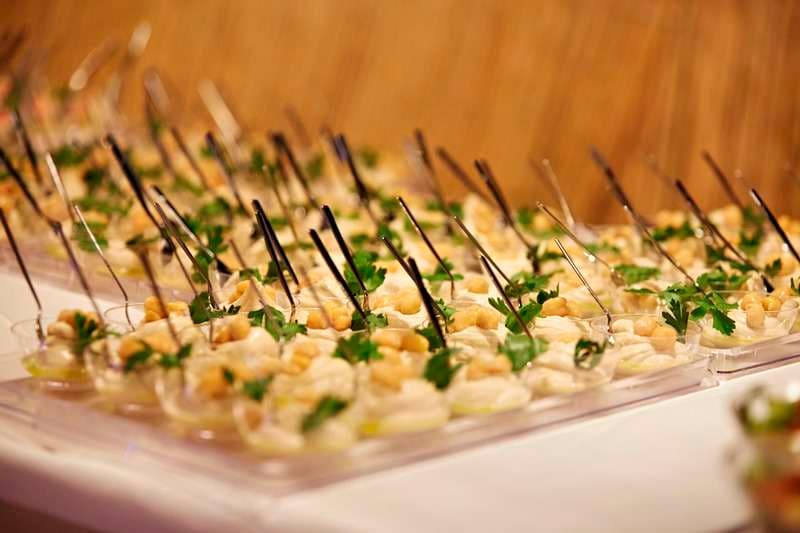 Individual cups of dip topped with chickpeas and parsley, with spoons, at Sporting Club Beach