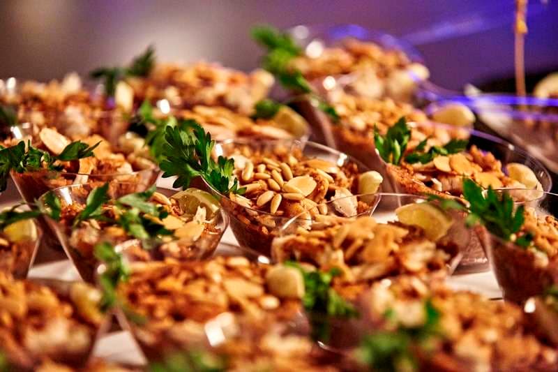 Individual cups topped with nuts and parsley with lime wedges at Sporting Club Beach