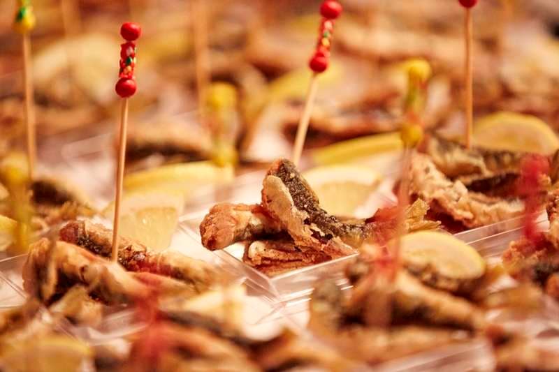 Fried small fish on cocktail picks with lemon in individual trays at Sporting Club Beach