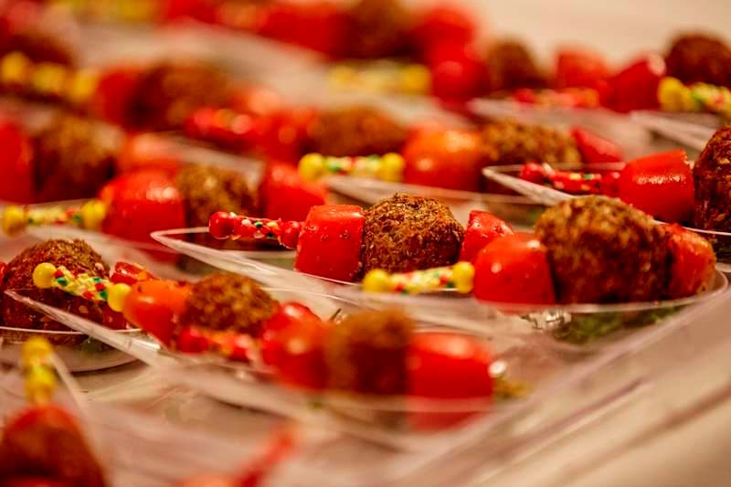 Cherry tomato and fried bite skewers on individual spoons at Sporting Club Beach