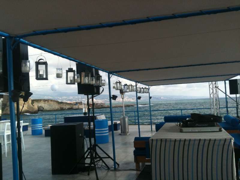 An outdoor seaside banquet at sunset with the Beirut coastline behind at Sporting Club Beach