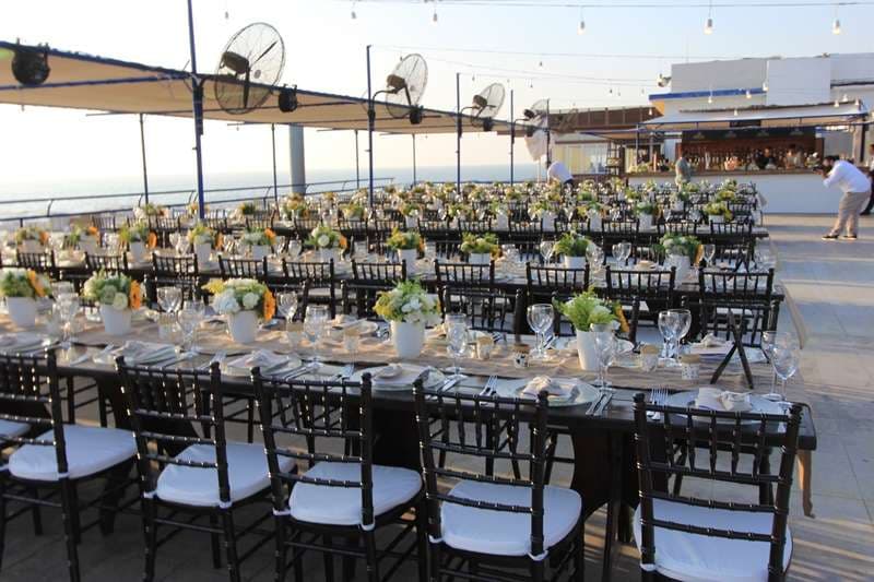 An outdoor terrace banquet with sunflower centrepieces beside the sea at Sporting Club Beach