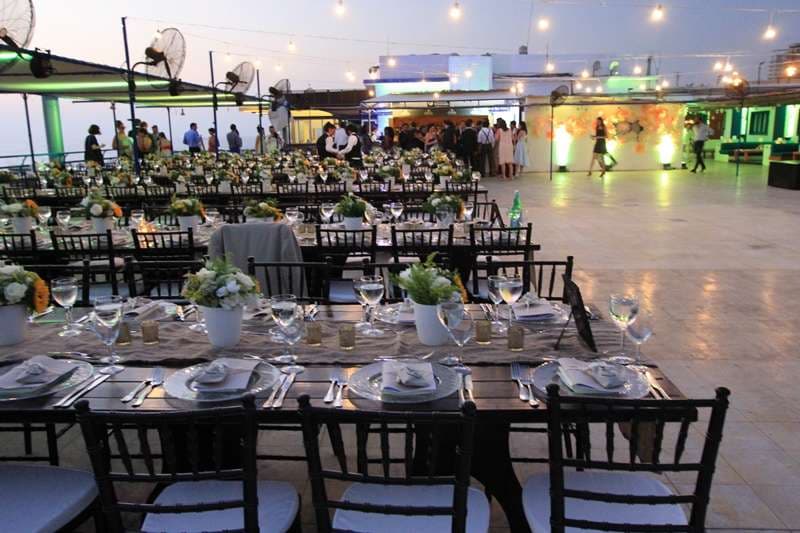 An outdoor terrace banquet with floral centrepieces and an open dancefloor at Sporting Club Beach