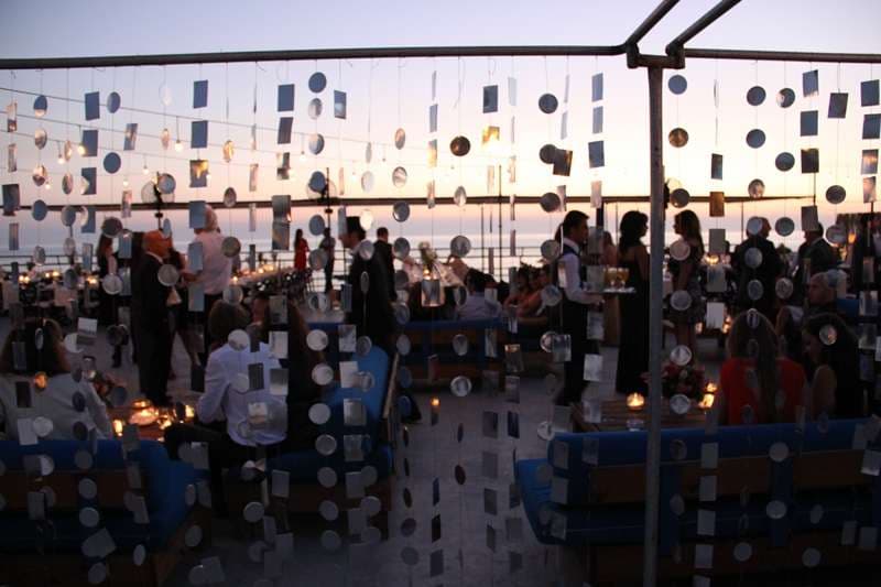 An outdoor evening event with hanging decorations and lounge seating at Sporting Club Beach